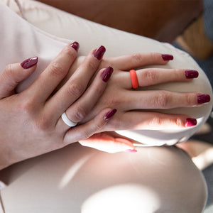 A lady's hands with white and coral E3 active silicone wedding rings
