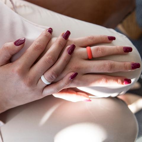 A lady's hands with white and coral E3 silicone wedding rings